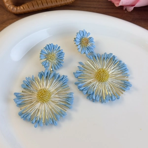 Detail view of sky blue flower drop earrings with golden pistils for beach vacation style