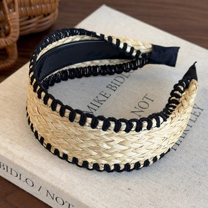 Close-up of bohemian straw headband with black woven edges on a vintage book