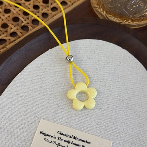 Primer plano del colgante de flor amarilla con cordón de cera y cuenta de metal pulido