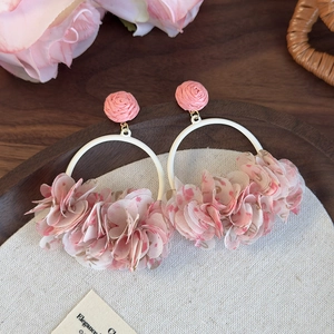 Close-up of pink fabric floral petals and metallic ring hoop on bohemian earrings