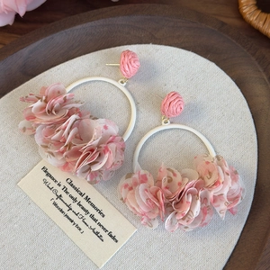 Macro detail of oversized floral hoop earrings with pink chiffon flowers and fabric petals