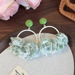 Detail showing white circular earrings with delicate green fabric flower petals