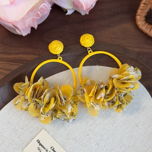 Detail of yellow fabric floral hoop earrings with sheer petals on a rustic background