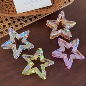 Macro detail of holographic star-shaped hair claws in four colors on a wooden surface