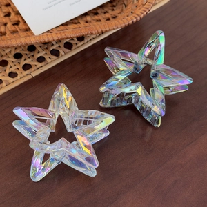 Detailed view of iridescent star-shaped hair claws on a wood background with high shine