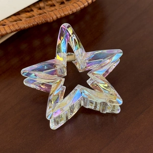 Macro shot of colorful iridescent star hair claw with gold spring on a wooden background