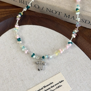 Collier en perles de résine colorées avec pendentif nœud argenté sur support en tissu