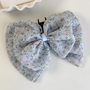Detailansicht der floralen Chiffon-Schleife-Haarklammer mit zartrosa Blumen auf Hellblau