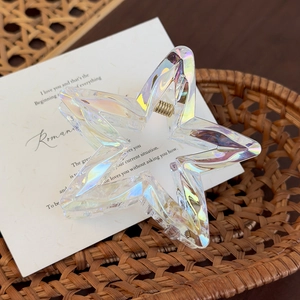 Macro detail of iridescent star hair claw clip with golden spring on woven basket