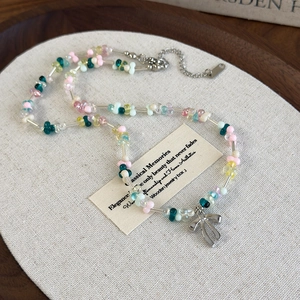 Collier de perles colorées en résine avec pendentif nœud argenté sur un plateau en bois
