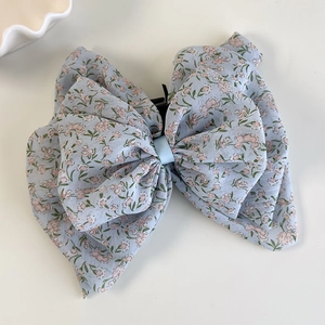 Makro-Detail des hellblauen Blumen-Chiffonstoffs am großen Schleifen-Haarclip-Accessoire