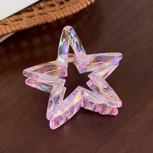 Close-up of iridescent pink star hair claw clip made of acrylic on a dark wood surface