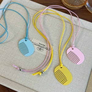 Detail of colorful comb shaped pendants in blue yellow and pink with braided ropes