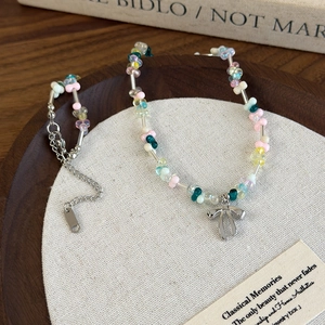 Détail de perles en résine colorées et pendentif nœud argenté sur fond vintage