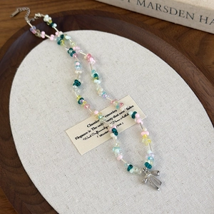 Détail du collier de perles en résine colorées et tubes en métal avec pendentif nœud