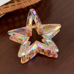 Macro side view of a colorful star-shaped acrylic hair claw on a brown wooden table