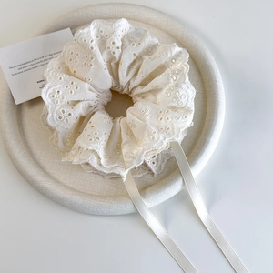 Close-up of cream lace scrunchie with layered ruffles and long elegant streamers