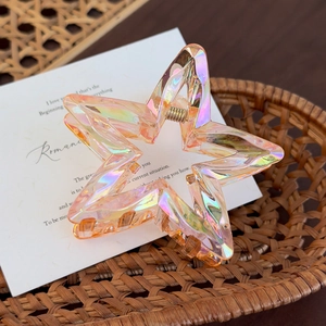 Macro shot of colorful holographic acrylic star hair claw clip with metallic spring detail