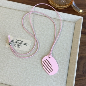 Detail of creative pink acrylic comb pendant necklace with matching woven cord