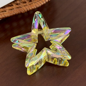 Detail view of a yellow holographic star hair claw clip with colorful iridescent coating