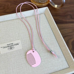 Detailed view of creative pink comb pendant on a matching necklace cord with bead detail