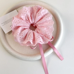 Close-up of pink lace scrunchie with layered embroidery and long flowing ribbons