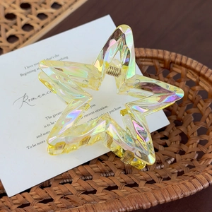 Macro detail of iridescent star-shaped hair claw clip with golden metal spring