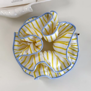 Detail eines gelb-weiß gestreiften Scrunchies mit hellblauem Kontrast-Saum