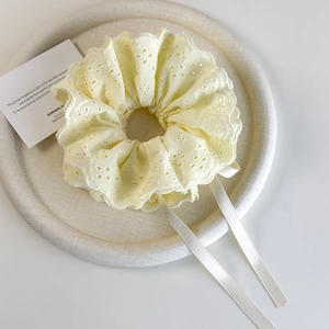 Detail of candy-colored lace scrunchie with ribbons on a textured display tray