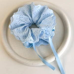 Detail of light blue floral lace scrunchie with ribbons and delicate embroidery