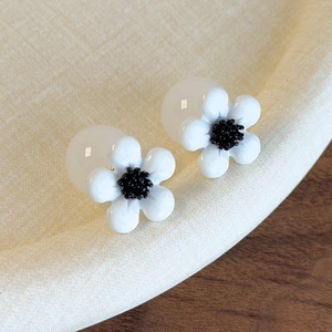 Detailed close-up of cherry blossom resin earrings with black center and bead backings