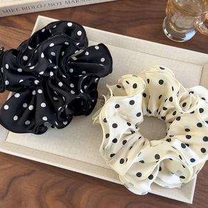 Close-up of black and white polka dot chiffon scrunchies with pleated texture and ruffles