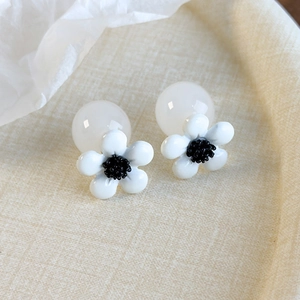 Detailed macro view of resin flower stud earrings with large white pearl bead backings
