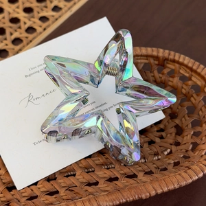 Detailed macro view of iridescent star-shaped hair claw clip with silver metal spring