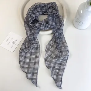 Elegant skinny black and gray plaid scarf made of lightweight fabric on a white dish