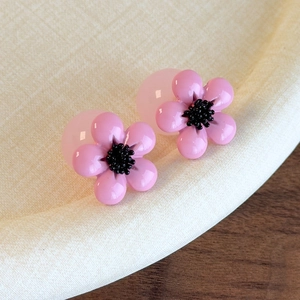 Detail view of pink resin cherry blossom earrings with double-sided transparent beads