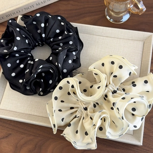 Detailed view of black and beige polka dot scrunchies with soft ruffled fabric texture