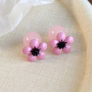 Macro view of pink resin flower earrings with unique double-bead base and translucent finish