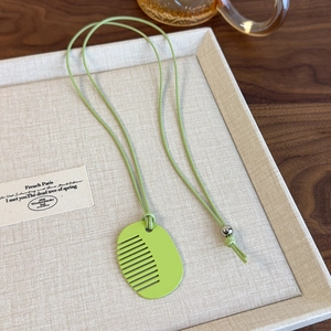Macro shot of grass green comb pendant necklace with adjustable silver bead detail