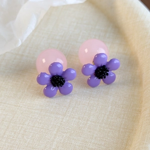 Detail view of purple resin flower earrings with pink translucent round backings