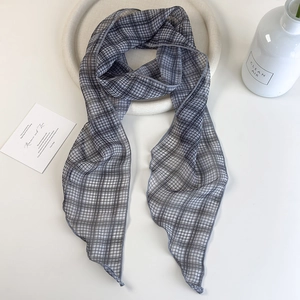 Close-up of lightweight grey checkered skinny silk scarf on a minimalist white table setup