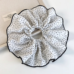 Dettaglio dell'elastico scrunchie in chiffon bianco a pois neri con bordo rifinito