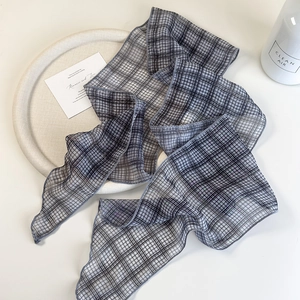 Detailed close-up of dark grey checked narrow scarf on a minimalist white background
