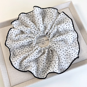 Dettaglio di scrunchie in rete bianca a pois neri con cuciture sottili sui bordi