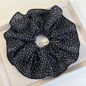 Dettaglio di un elastico per capelli XL in chiffon a pois neri con cuciture fini