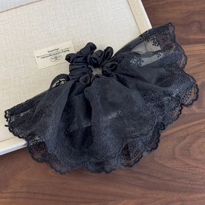 Détail d'un chouchou en dentelle noire élégante avec broderies florales et satin