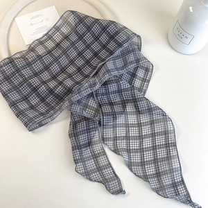 Macro shot of grey plaid narrow scarf fabric showing light mesh texture and edge stitching