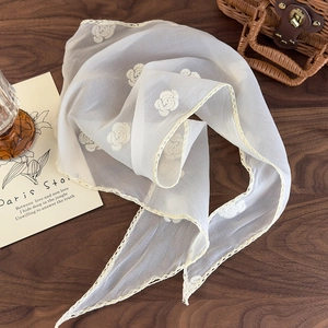 Detail of white semi-transparent floral head scarf with lace trim on a rustic table