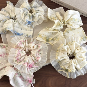 Detailed view of floral scrunchies with ribbons and buttons on a gray tray