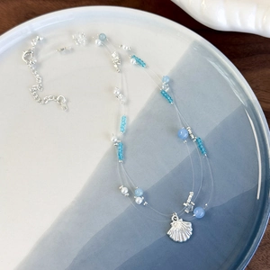 Detail of multi-strand ocean necklace with blue crystal beads and silver shell charm